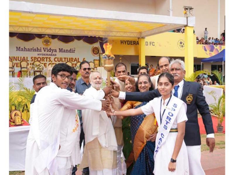 Brahmachari Dr. Girish Chandra Varma Ji, the Honourable Chairman of Maharishi Group of Institutions, graced the Silver Jubilee Celebrations of Maharishi Vidya Mandir, Kondapur, Hyderabad, on December 7, 2024, at the GMC Balayogi Athletic Stadium, Gachibowli, Hyderabad. The event also marked the school’s Annual Sports & Cultural Day, with more than 3000 students from Nursery to Class XII participating in various cultural and sports activities.
The program began with the lighting of the ceremonial lamp by Brahmachari Dr. Girish Ji, along with the school’s Principal, Mrs. Vasanthy Parasuraman, and Directors of Maharishi Vidya Mandir Schools Group, followed by Guru Pujan. Brahmachari Dr. Girish Ji then hoisted the sports flag, marking the commencement of the day’s events, which included a march past by the students led by the school’s NCC cadets.
The Principal, Mrs. Vasanthy Parasuraman, delivered the welcome address, highlighting the growth and achievements of Maharishi Vidya Mandir, Hyderabad, over the past 25 years and its reputation for quality education and discipline. This was followed by an address by Brahmachari Dr. Girish Ji, who congratulated the school on its milestone and praised the efforts of the students, staff, and parents in maintaining its excellence.
The event was attended by over 8000 parents and guests, who witnessed the celebrations and performances, making the occasion memorable and grand.
